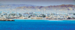 Somaliland 5 Day Nature and Culture Tour A picturesque coastal city stretches along a beach, with mountains in the background and blue water in the foreground.