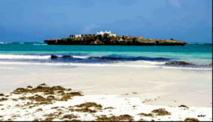 Mogadishu and Somalia Express Economy Tour and Local Sites and Highlights A scenic view of a tropical beach with white sand, turquoise water, and an island with a white building on it under a blue sky.