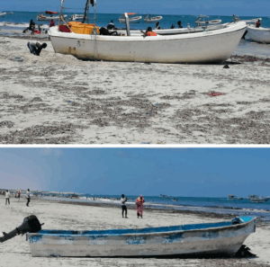 Somalia Boat Rental – Boat Hire (Boat Charter) The image shows two boats on a sandy beach with seaweed, people and water in the background under a bright sky.